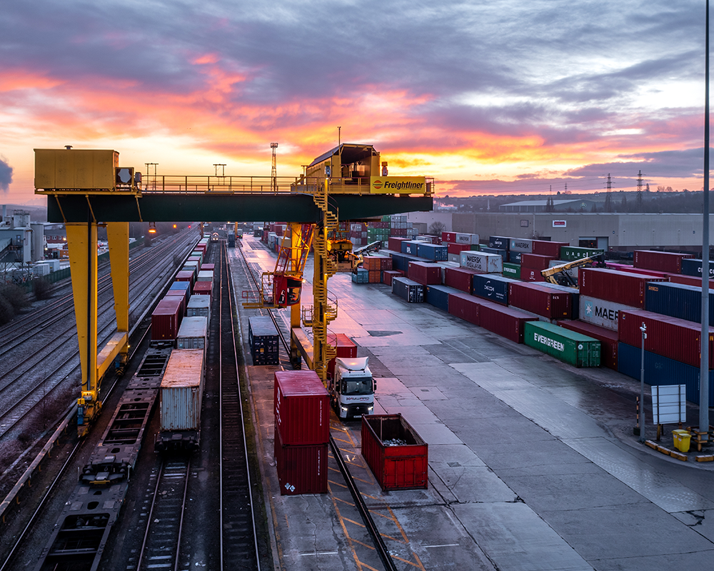 Bird’s-eye view of intermodal logistics yard with containers and rail access